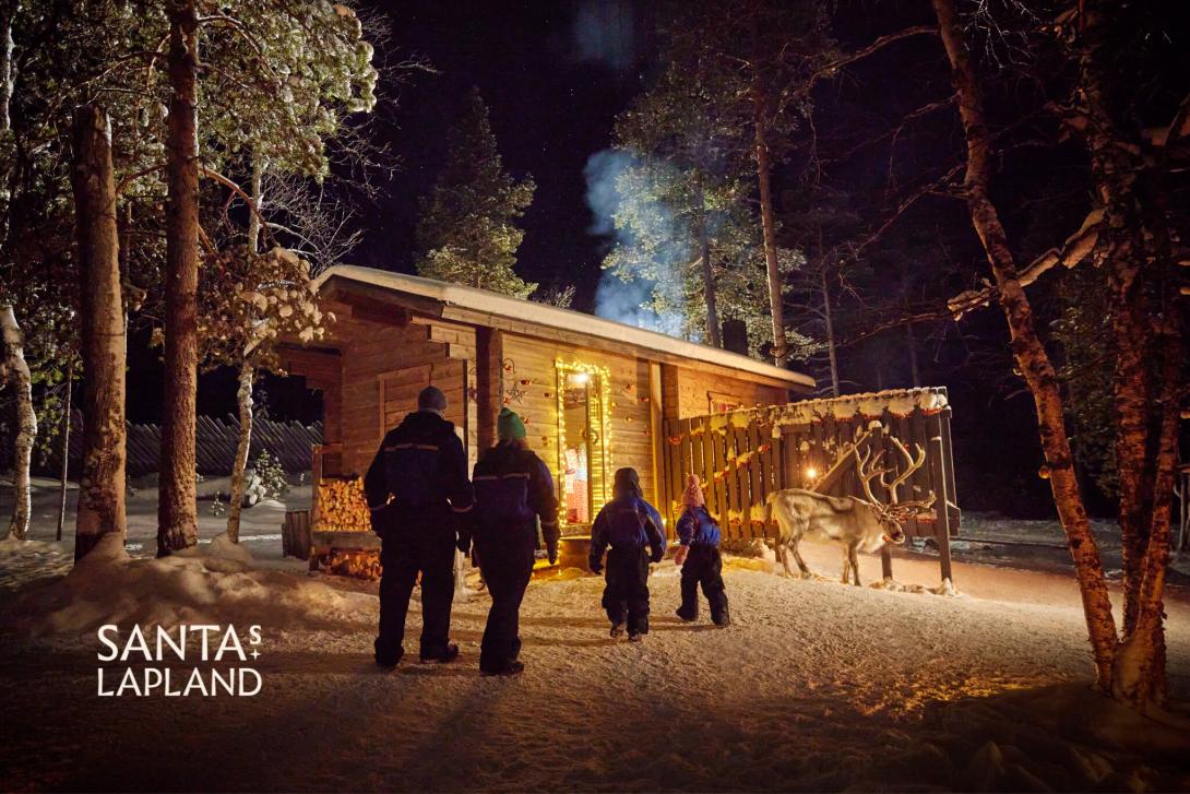 A family walk towards a cabin in the woods at Santa's Lapland