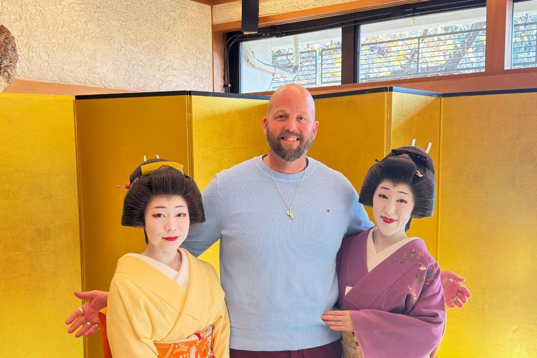 Man smiling with two Geisha women