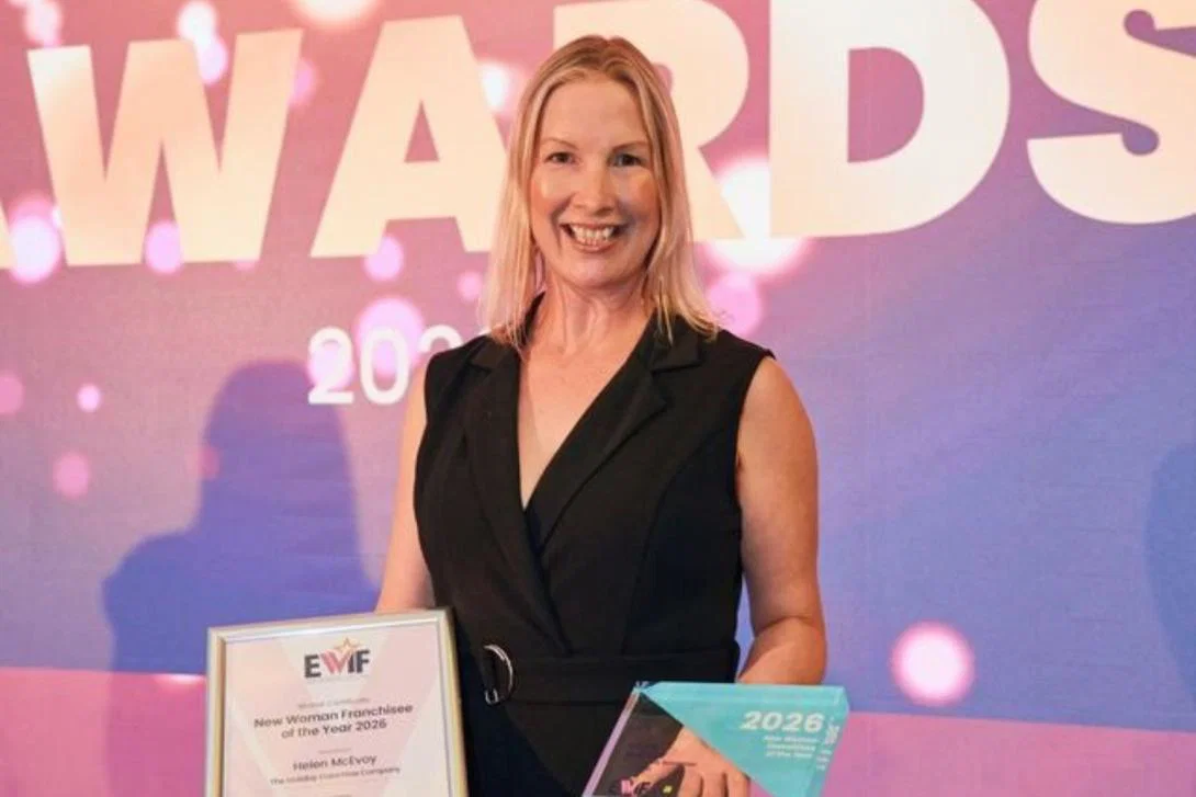 Woman with blonde hair smiling and holding two award plaques