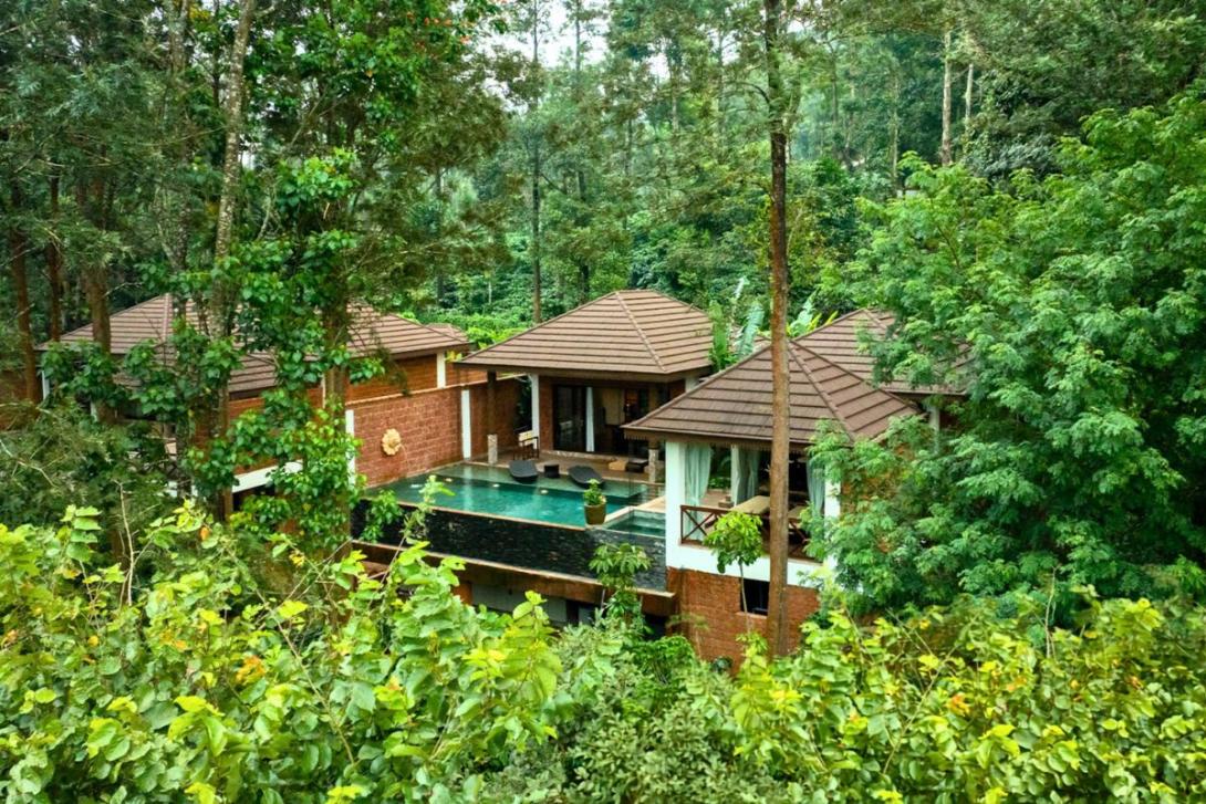 Aerial shot of villa with pool in lush greenery