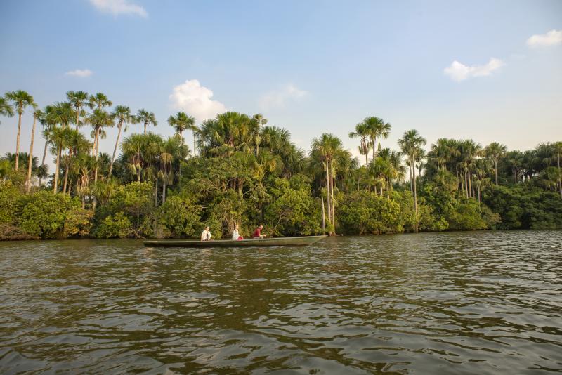 Two people in a boat in with Amazon rainforest in the background