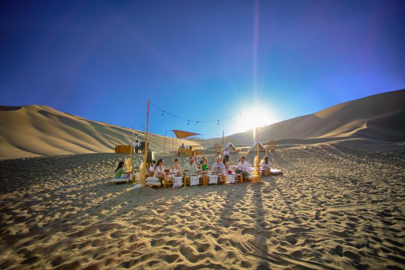 Group of people sit on sand in middle of desert