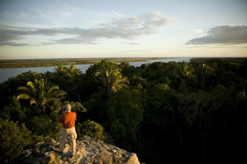 (credit: Travel Belize) Man stands on rock overlooking tropical treetops