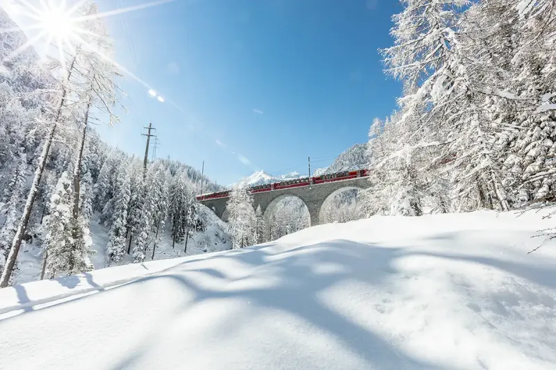 The Bernina Express passing through a snowy landscape