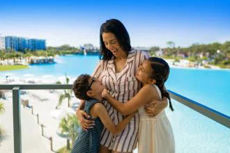 Mum and daughters hugging on a balcony with pool in background